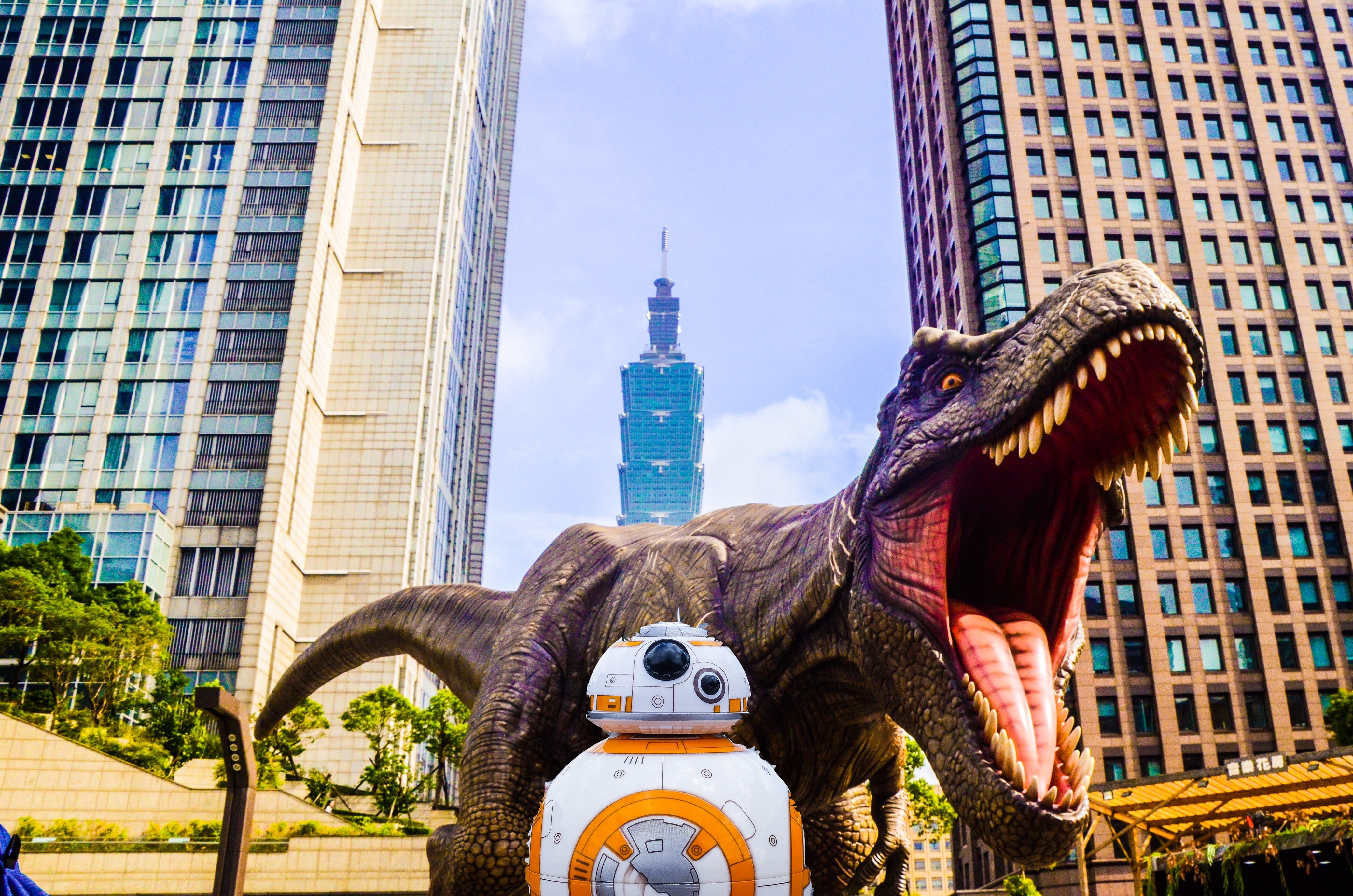 T-rex and BB8 pose in front of skyscrapers